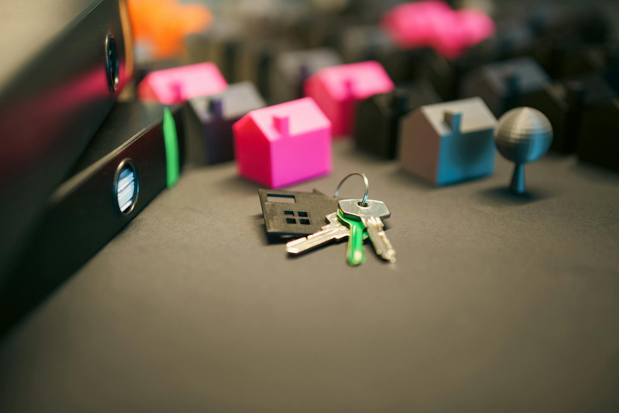 Miniature model houses and keys on a desk, symbolizing real estate and property investment.